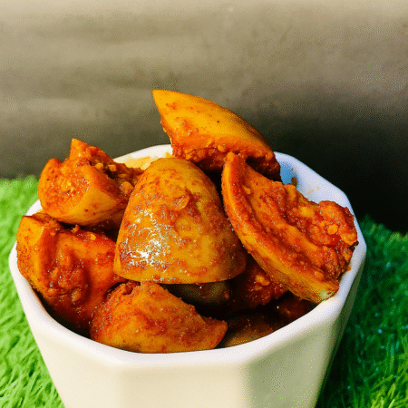 Jar of homemade mango pickle with traditional spices and sliced mango pieces.